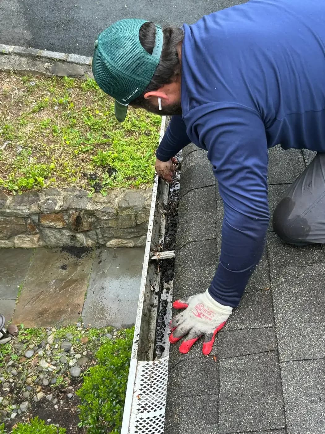 Haus Prime technician clearing debris out of a gutter by hand on a New Jersey roof